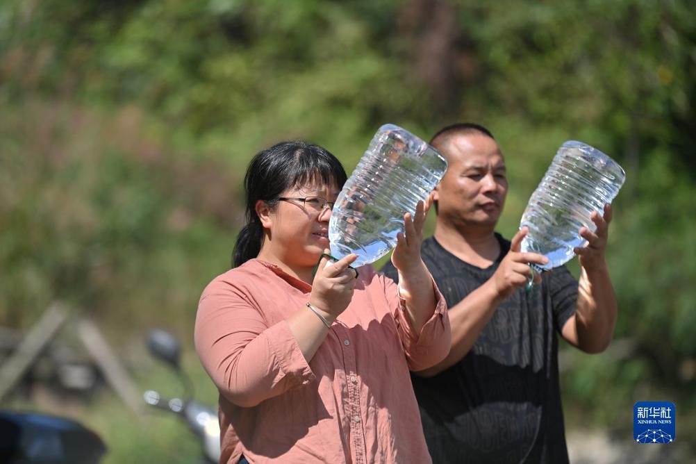 楊寧（左）在查看村民剛剛采集的水樣，為山泉水引水工程做準(zhǔn)備（10月8日攝）。新華社記者 黃孝邦 攝